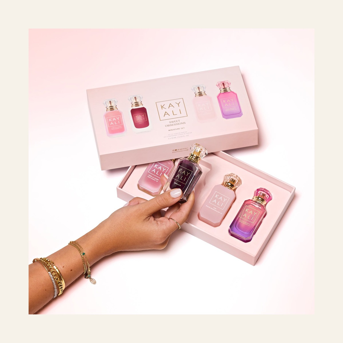 Open KAYALI Sweet Obsessions gift box with four miniature fragrances and a hand holding Vanilla 28