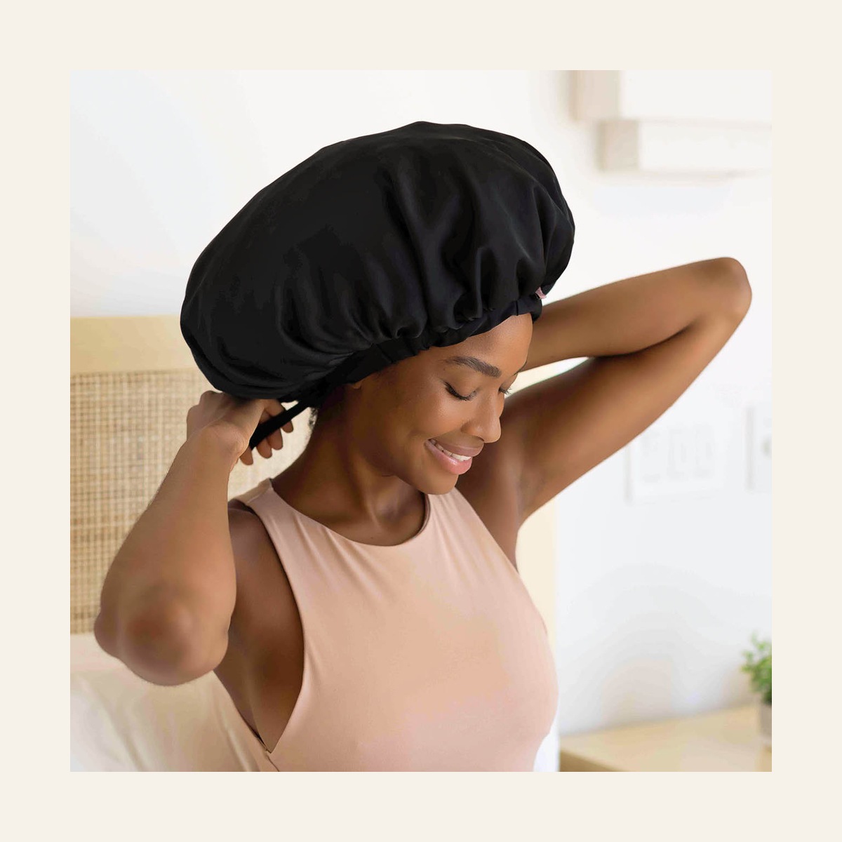Model adjusting the ties of the black XL satin bonnet at the back of her head
