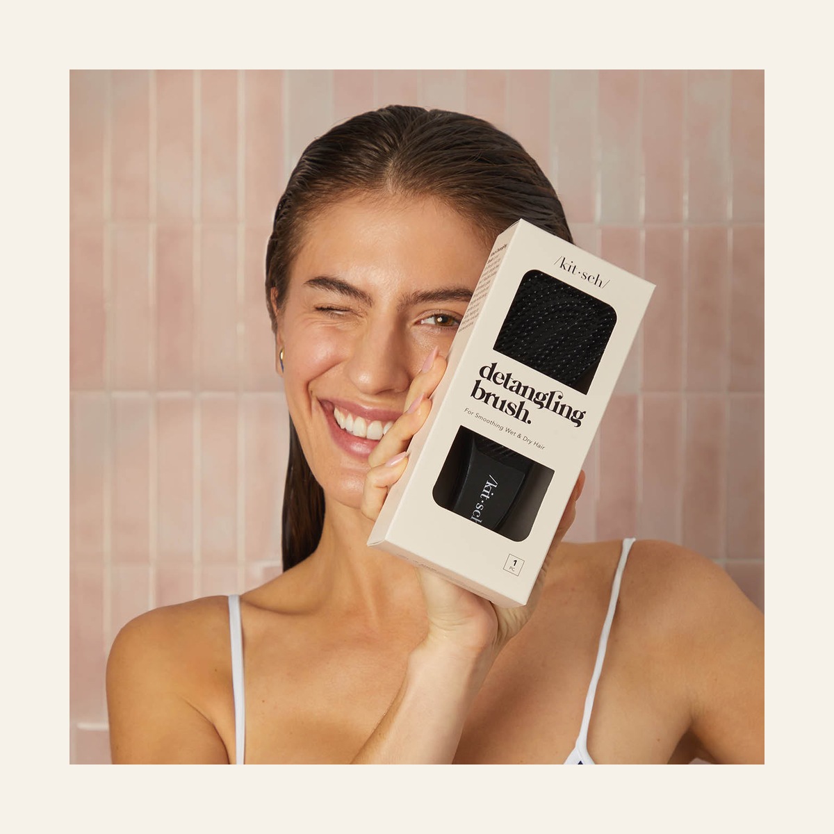 Model holding the black Kitsch detangling brush in its retail packaging